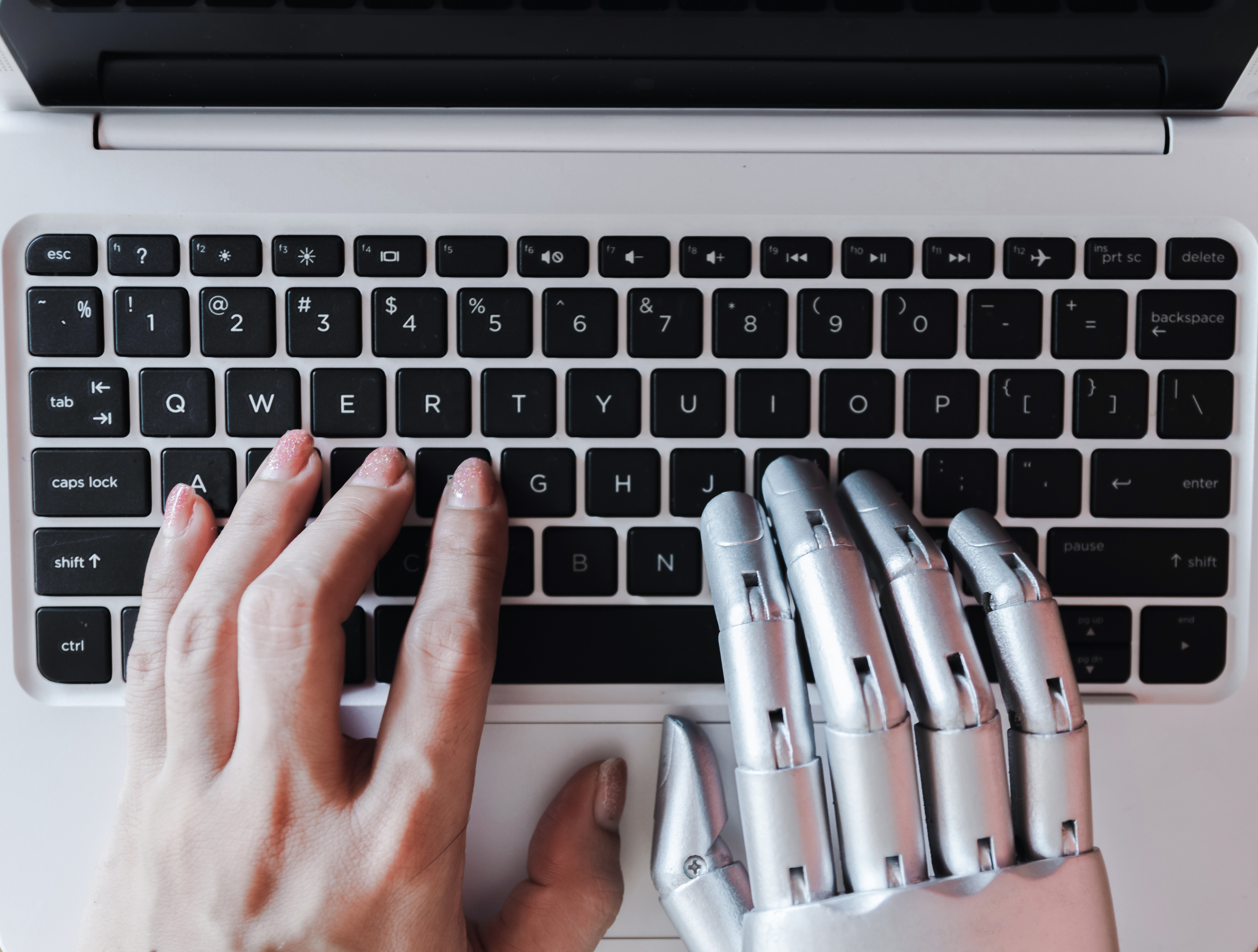 image of human and robot hands typing